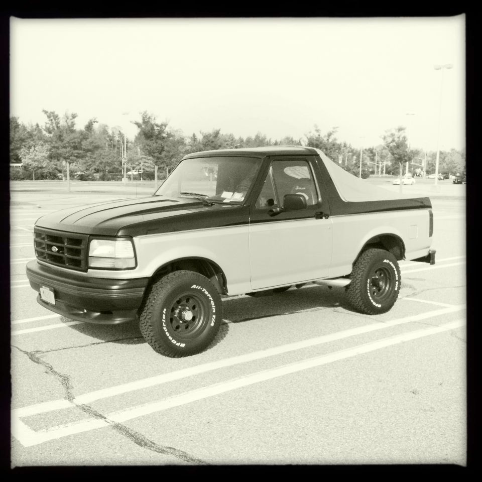 Two-tone 1992 Ford Bronco parked in a lot, side view