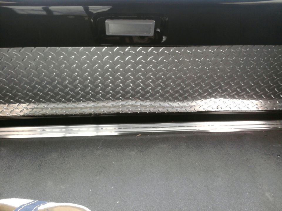 Diamond-plate tailgate trim panel and chrome rocker sill on a vehicle