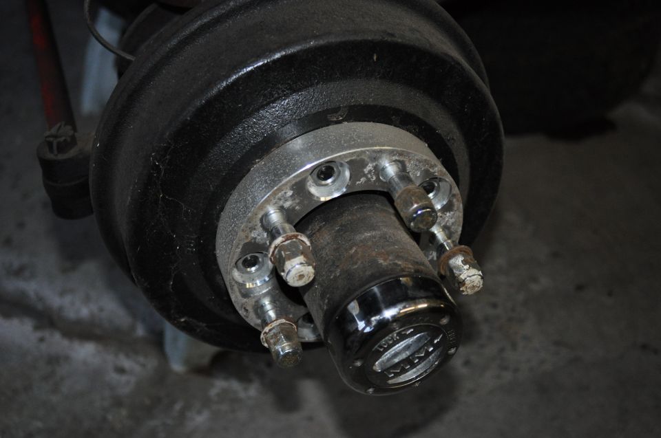 Close-up of a vehicle's front hub with lug nuts and a locking mechanism