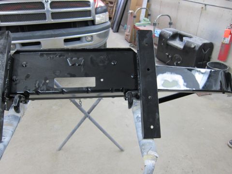 1987 Dodge 1500 - A black painted metal frame assembly is shown in a workshop, with a portion of a Dodge Ram truck visible behind it.