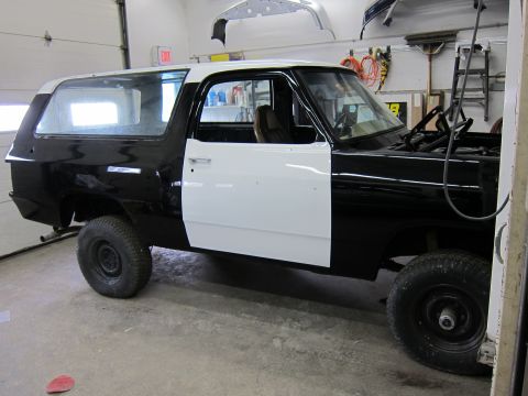 1987 Dodge 1500 - This 1987 Dodge Ramcharger is undergoing bodywork in a garage, with one side painted black and the other in white primer.