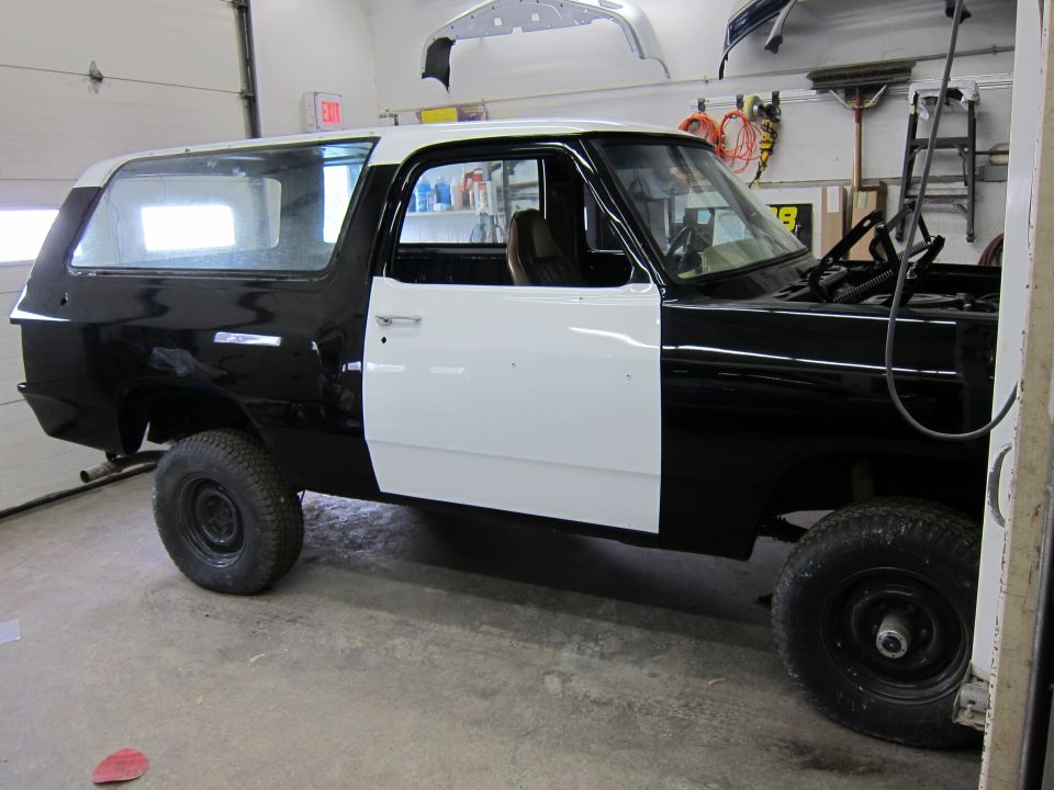 1987 Dodge Ramcharger in black and white primer, hood open, in a garage