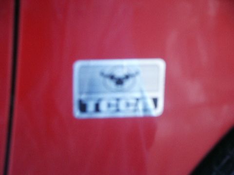 1998 Mercury Sable - A close-up of a red car's body panel shows a blurry badge with text that may read 'TOYOTA'.
