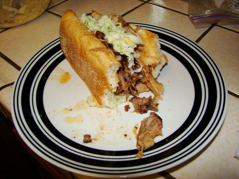 1989 Ford Bronco - A pulled pork sandwich with coleslaw sits on a plate with a bite taken out of it.