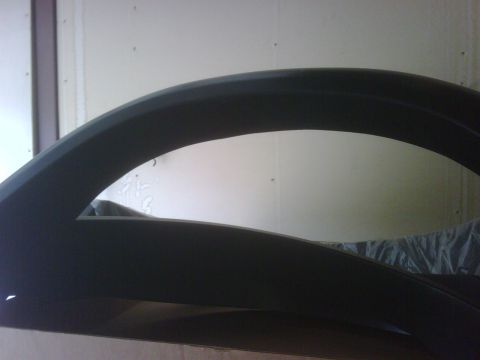 1996 Ford Bronco - A black fender flare is shown in a close-up, angled shot against a light-colored wall.