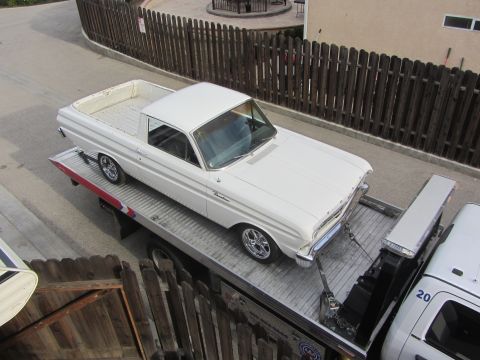1964 Ford Ranchero - A white 1964 Ford Ranchero is loaded onto a tow truck, secured with chains and straps.