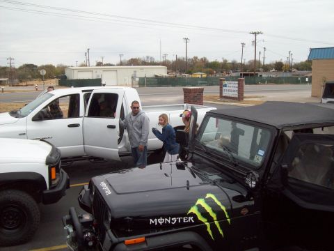 1989 Ford Bronco - A black Jeep Wrangler with prominent Monster Energy decals is parked next to a white pickup truck.
