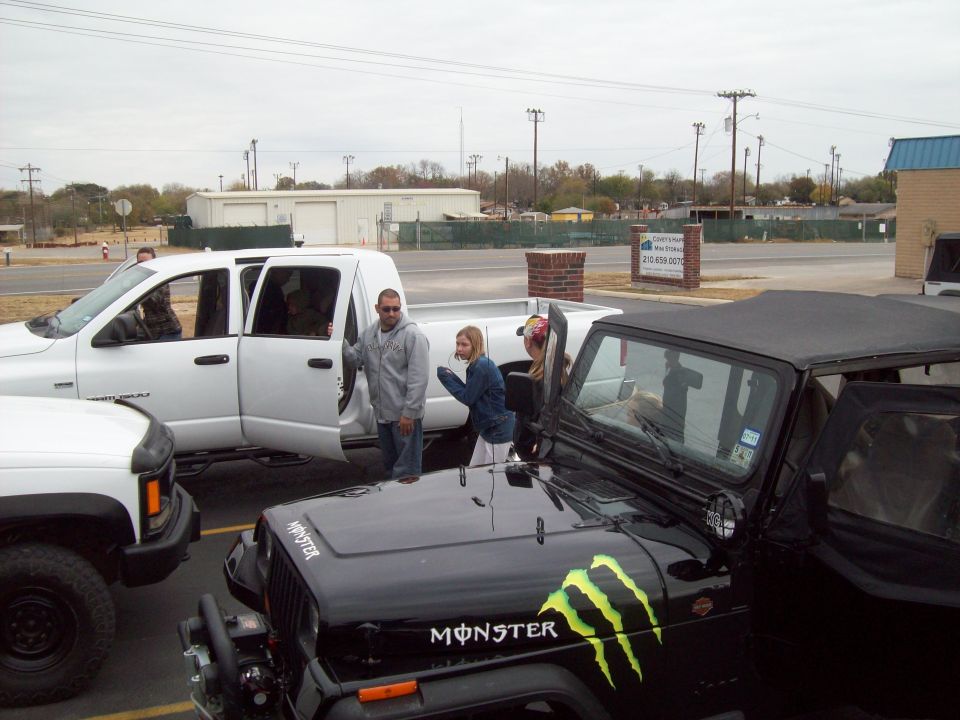 Black Jeep Wrangler with Monster Energy decals, front 3/4 view