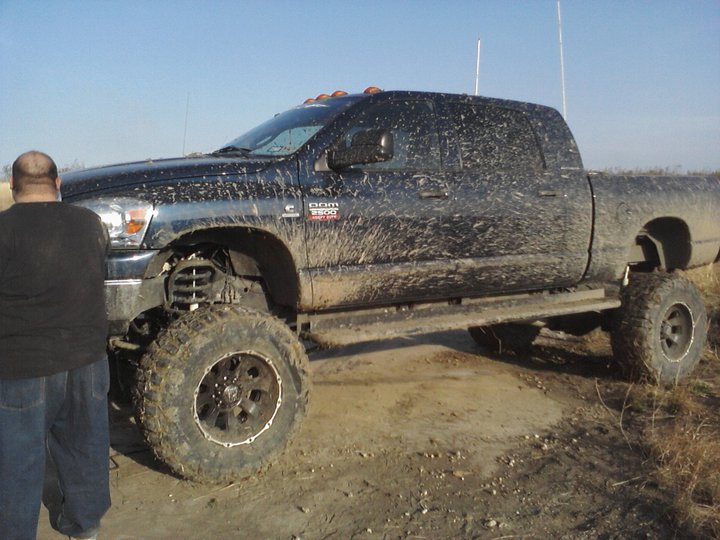 Muddy black Dodge Ram 3500 pickup truck with lifted suspension and large tires