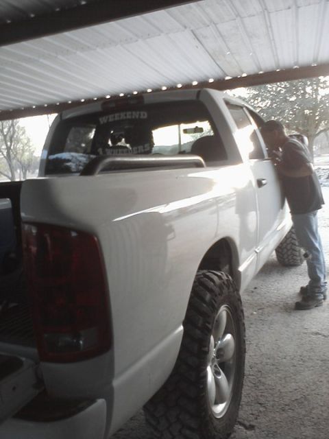 1989 Ford Bronco - A man leans into the driver's side window of a white pickup truck parked under a covered area.
