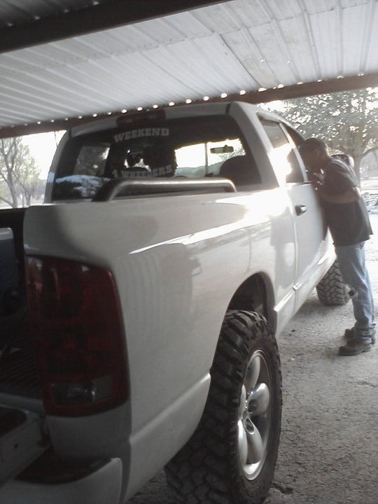 White pickup truck with "WEEKEND" sticker on rear window, guy looking in driver's side window