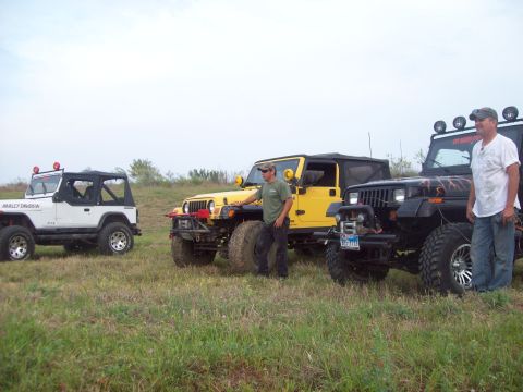 1989 Ford Bronco - Three Jeeps are parked in a field with two men standing near them.