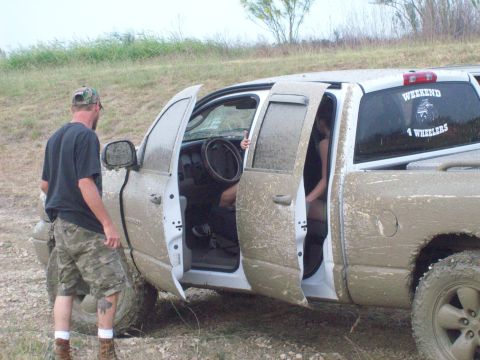 1989 Ford Bronco - A white pickup truck is covered in mud, with all four doors open, suggesting it has been off-roading.