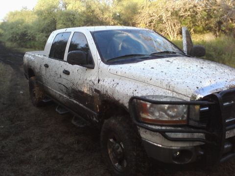 1989 Ford Bronco - This white pickup truck is heavily covered in mud after driving off-road.