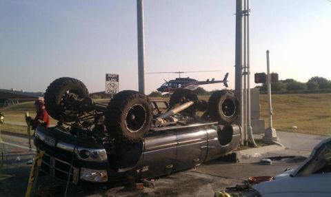 1989 Ford Bronco - A truck has overturned on the road, with a helicopter in the sky and emergency personnel nearby.