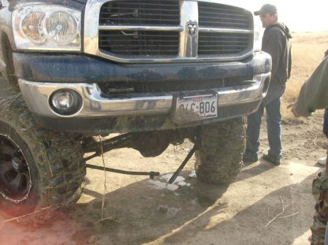 1989 Ford Bronco - A lifted pickup truck with oversized tires is shown from the front, with two people standing nearby.