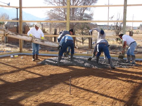 1995 Ford Bronco - Workers spread freshly poured concrete for a building foundation, with mountains in the background.