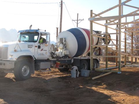 1995 Ford Bronco - A cement mixer truck is parked on a construction site next to a partially built wooden structure.