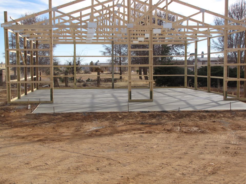 Wooden frame of a barn under construction with a concrete floor poured