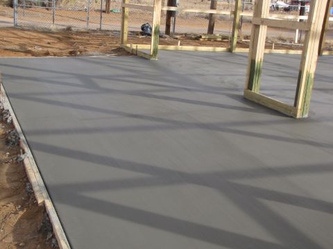 1995 Ford Bronco - A construction site shows a newly poured concrete slab with wooden framing for a building. The Supermotors logo is visible in the corner.