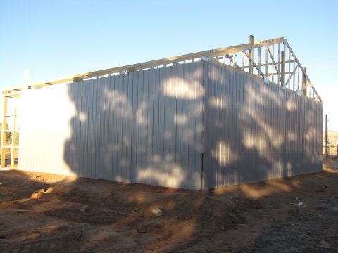 1995 Ford Bronco - A building is being constructed with metal siding and a wooden roof frame against a clear blue sky.