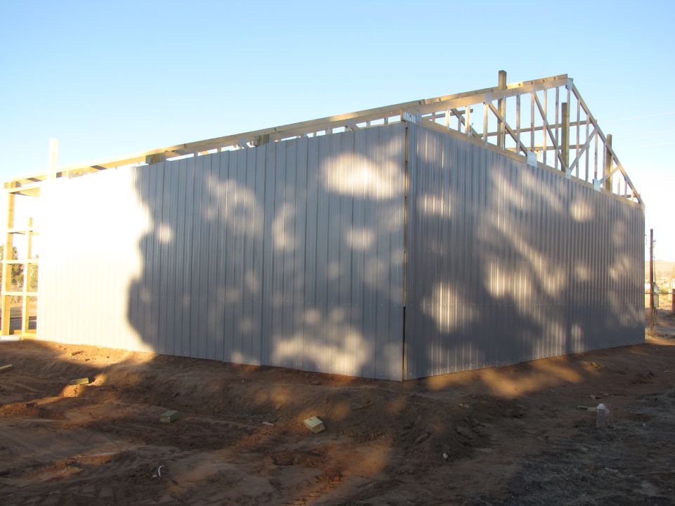 building under construction with metal siding and exposed wooden roof frame