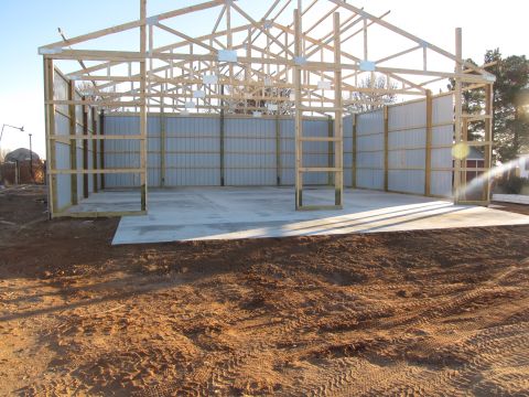 1995 Ford Bronco - Construction of a metal building with exposed wooden trusses and corrugated metal siding is underway, with a Supermotors.net logo visible.