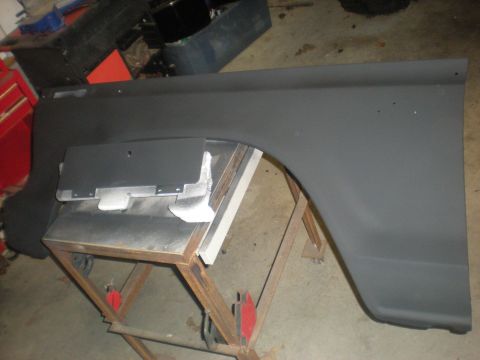 1978 Ford Bronco - A vehicle fender is prepped for painting, supported by a rolling stand in a garage setting.