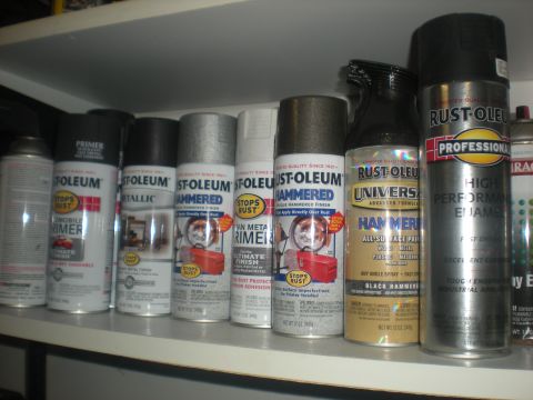 1978 Ford Bronco - A collection of spray paint cans from various brands and finishes are organized on a shelf.