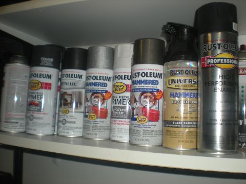 1978 Ford Bronco - Various Rust-Oleum spray paint cans, including primer, metallic, and hammered finishes, are neatly arranged on a shelf.