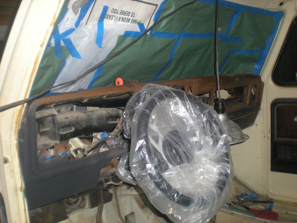 1978 Ford Bronco dashboard with steering wheel covered in plastic, undergoing repairs