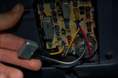 1992 Ford F-150 - A hand holds a relay near a vehicle's fuse box, showing various fuses and wiring.