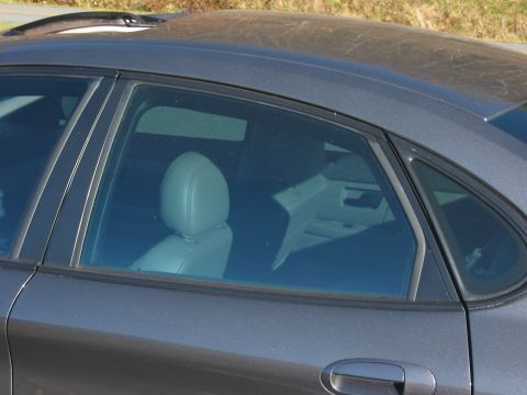 2003 Ford Taurus - The rear passenger side of a car is captured, revealing tinted windows and a glimpse of the interior seating.