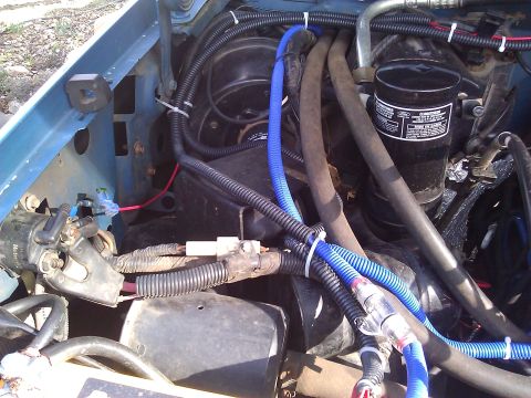 1992 Ford F-150 - Engine bay wiring with blue tubing and hoses visible, some text on a black cylinder.