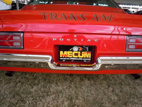 1982 Chevrolet Camaro - Rear view of a red Pontiac Trans Am, the 'Trans Am' script and a Mecum auction license plate.