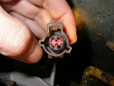 1990 Ford Bronco - A hand holds an electrical connector, revealing its internal pins and pink plastic housing.