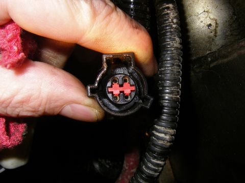 1990 Ford Bronco - A close-up shows an electrical connector with red inserts, held by a hand near a wire loom.