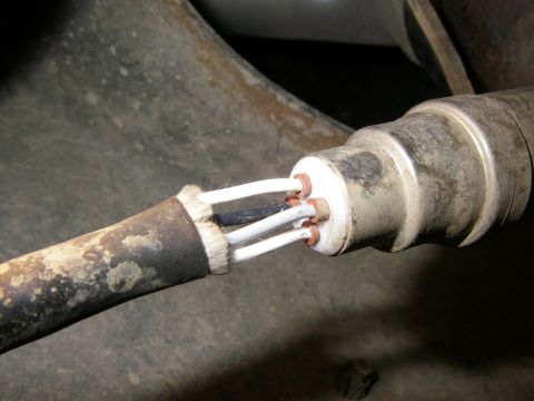 1990 Ford Bronco - The exposed wires of a vehicle's oxygen sensor are visible, connected to a white ceramic insulator.