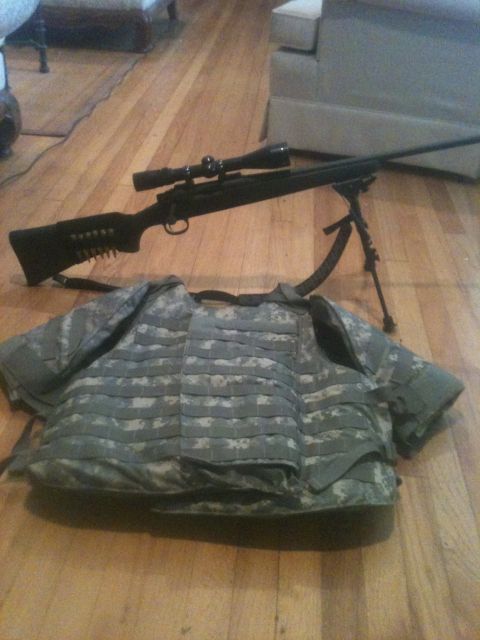 1993 Ford Bronco - A sniper rifle and tactical vest are laid out on a wooden floor, with furniture visible in the background.