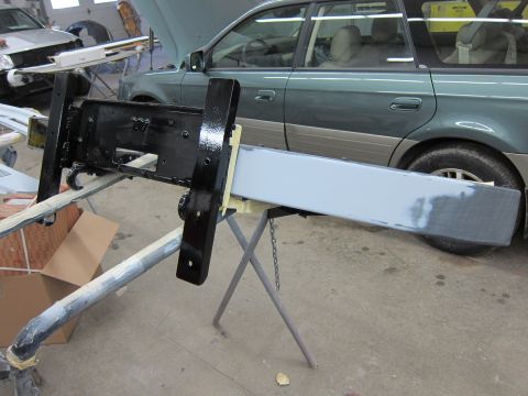 1987 Dodge 1500 - A vehicle bumper assembly is being worked on in a garage, with another vehicle visible in the background.