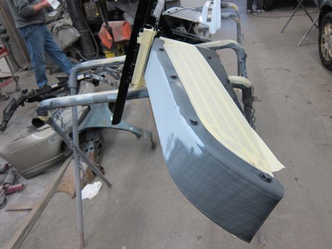 1987 Dodge 1500 - A car bumper is taped and sanded in a body shop, ready for primer and paint.