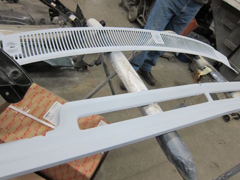 1987 Dodge 1500 - Car parts, including a grille and trim, are prepped for painting in a workshop.