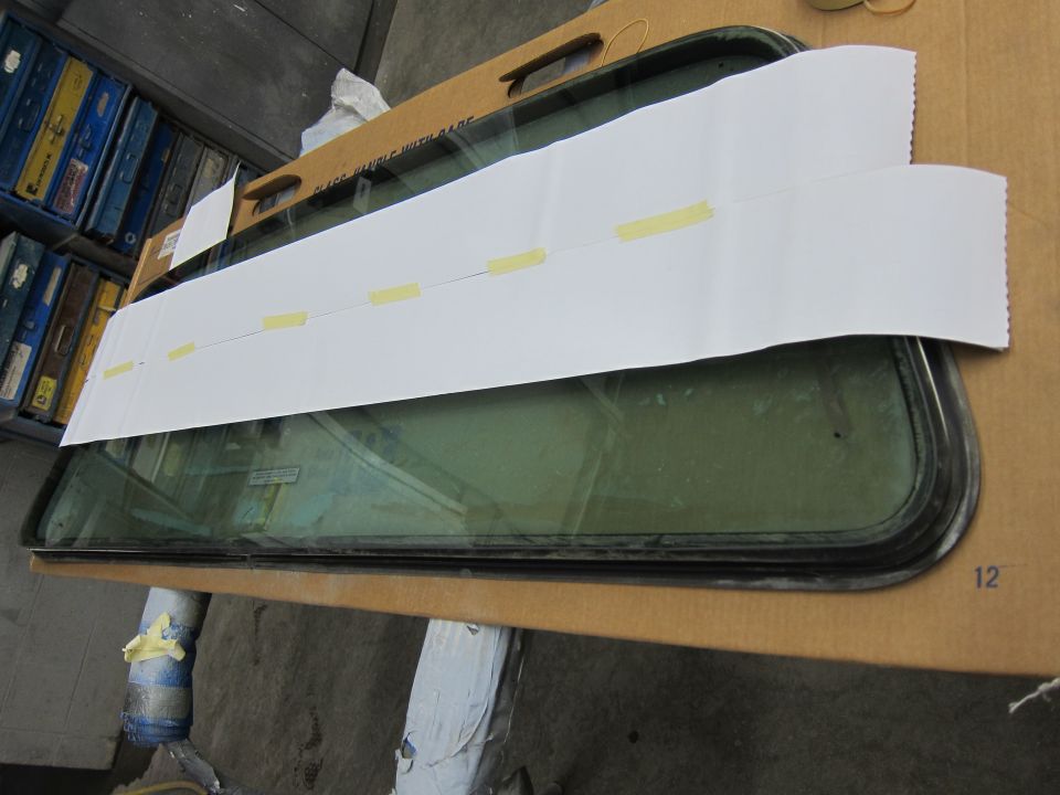 Car window with white paper taped over it, resting on cardboard