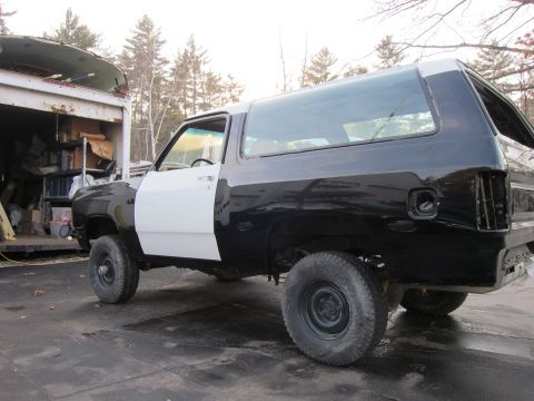 1987 Dodge 1500 - A two-tone Dodge Ramcharger is parked outside, showing its unfinished bodywork and interior.