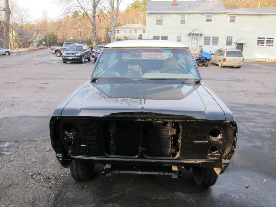 Front view of a black pickup truck with its grille removed. The vehicle appears to be undergoing some work