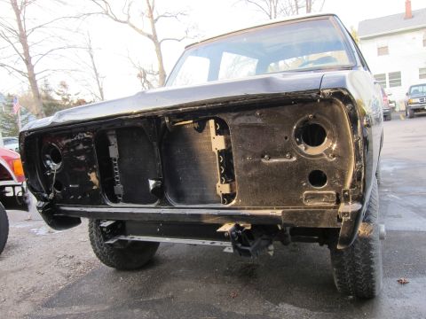 1987 Dodge 1500 - A black truck's front end is disassembled, revealing the inner workings of the radiator and headlight mounts.