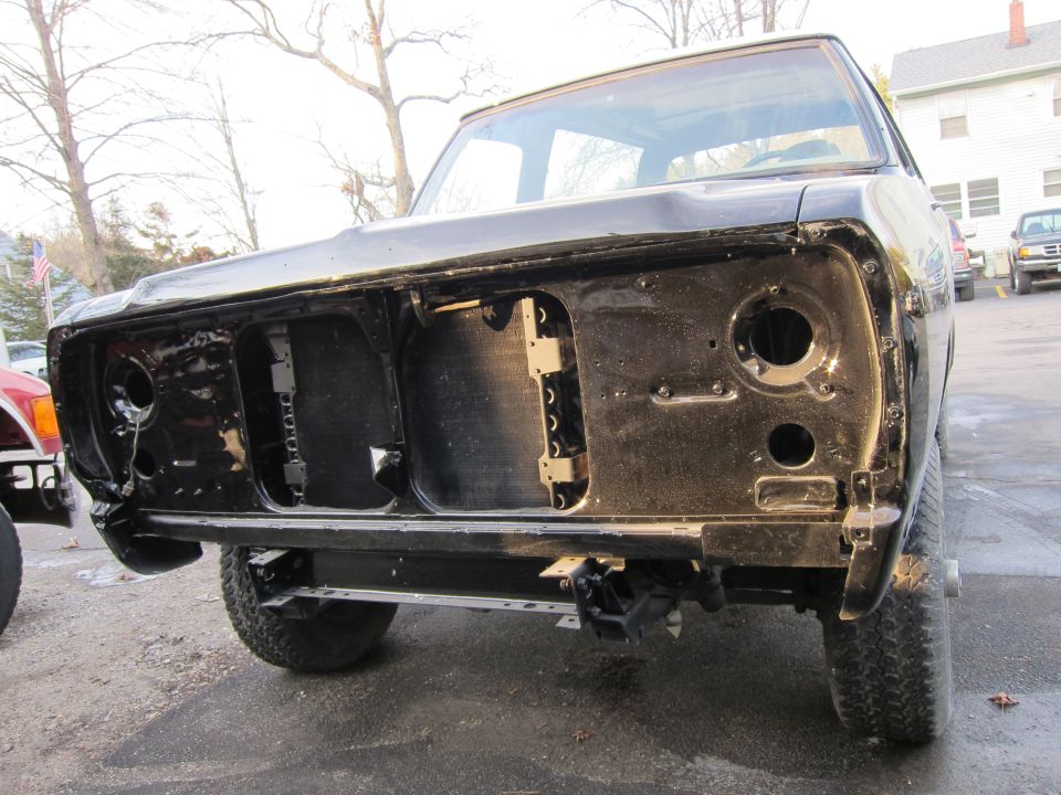 Black truck front end with grille removed, showing radiator support and headlight openings