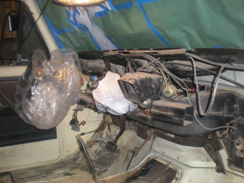 1978 Ford Bronco - The dashboard of a vehicle is shown with various components and wiring exposed, some covered for protection.