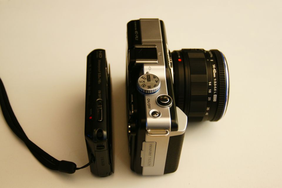 Compact digital camera next to a mirrorless camera with a lens attached
