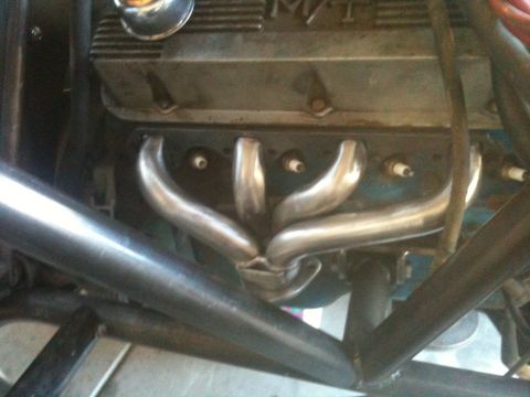 1966 Ford Bronco - The engine bay shows a V8 engine with custom exhaust headers and spark plug wires connected.
